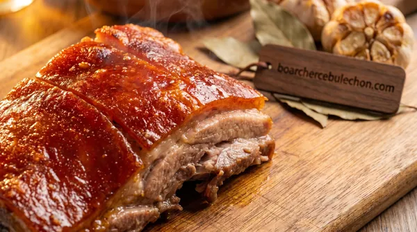 A slab of Cebu lechon sliced on a board with roasted garlic